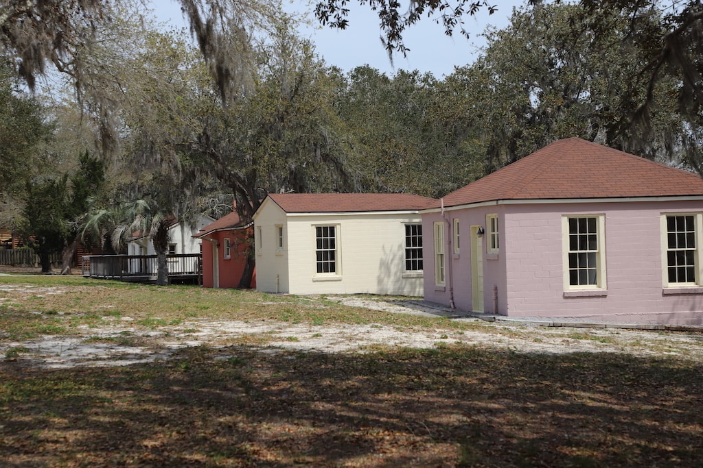 One pink, one white, and one rust colored old historic cottages.