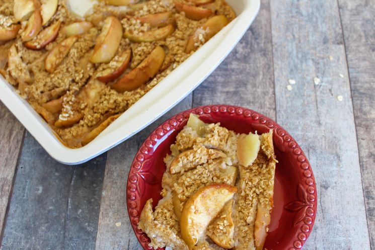 Apple crisp on a red plate with larger white plate on side.