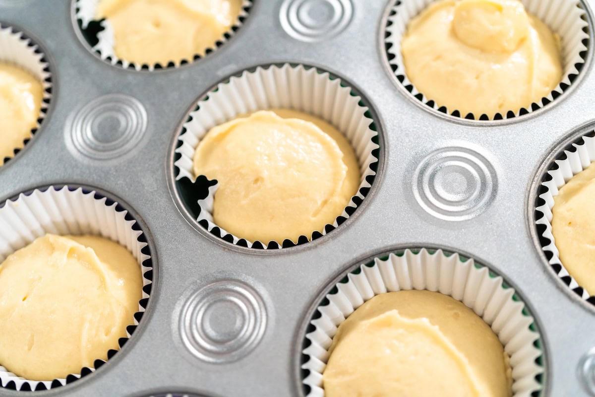 Yellow cupcake batter in liners in cupcake pan.