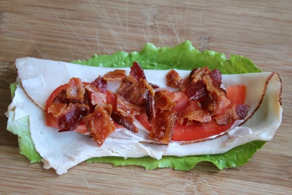 Lettuce topped with turkey, tomato, and bacon.