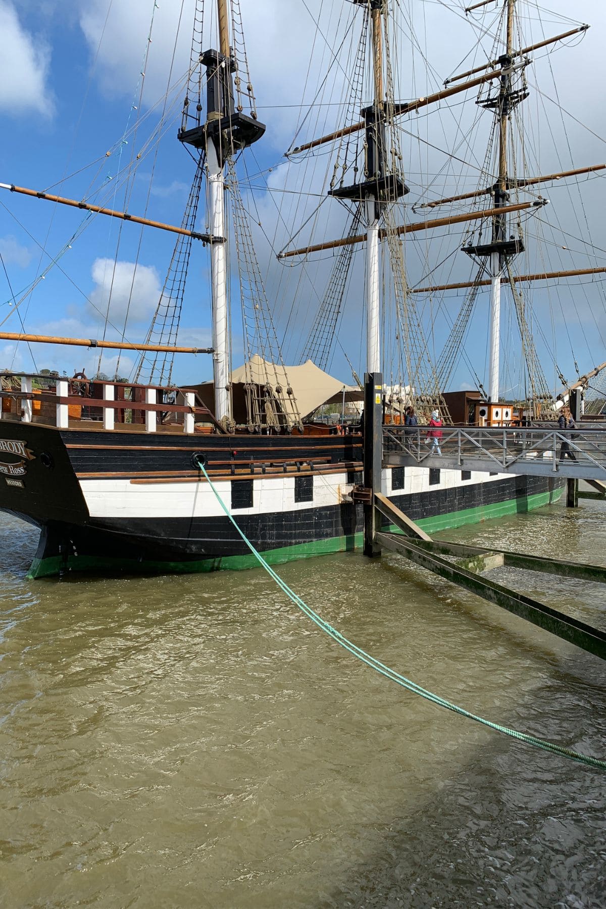 Old ship with sails down docked in a harbor.