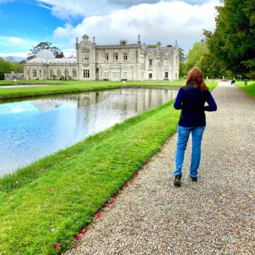 Woman walking along a lake in front of a castle.