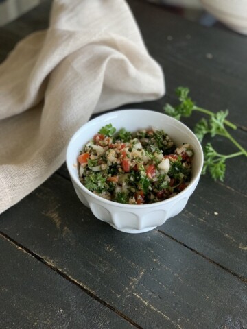 tabbouleh in white bowl on black table with napkin