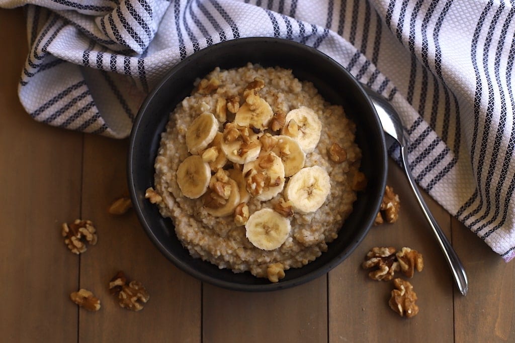 Banana nut oatmeal in a black bowl with a striped dishtowel.