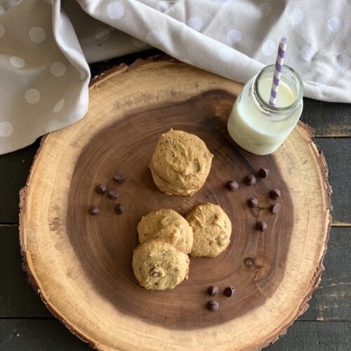 Cookies with a bottle of milk on a wood slab.