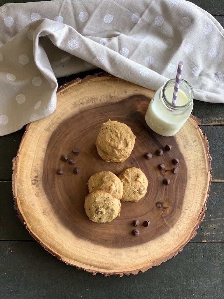 Cookies with a bottle of milk on a wood slab.