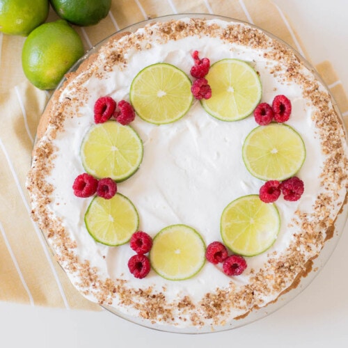 key lime pie with limes and raspberries on yellow napkin