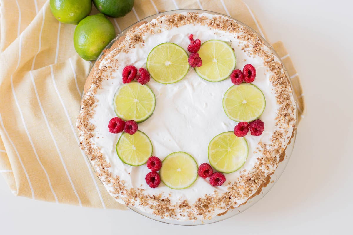 key lime pie with limes and raspberries on yellow napkin