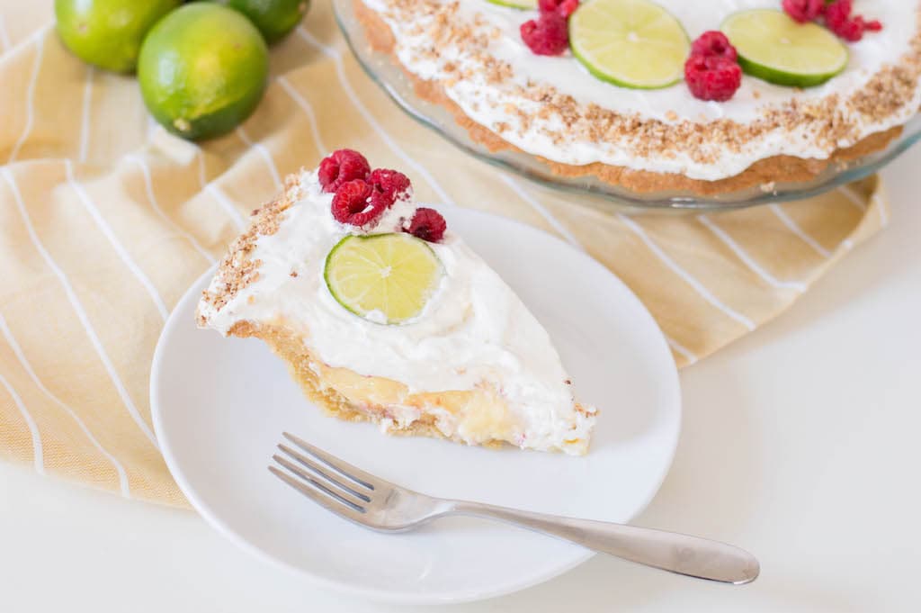 key lime pie with limes and raspberries on yellow napkin