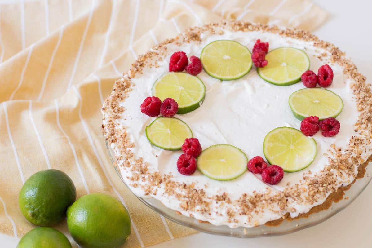 key lime pie with limes and raspberries on yellow napkin