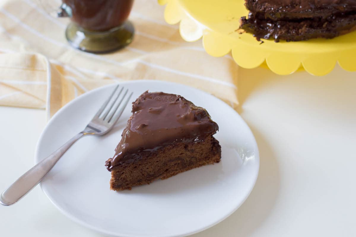 slice of sacher torte, chocolate cake with chocolate icing, on white plate
