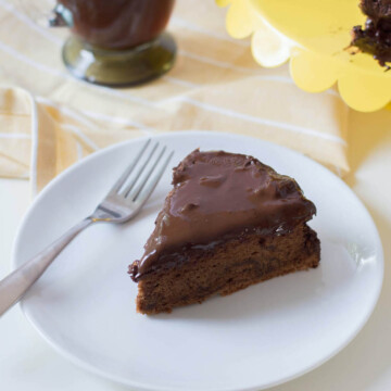 chocolate torte in white plate with yellow tray and coffee in background