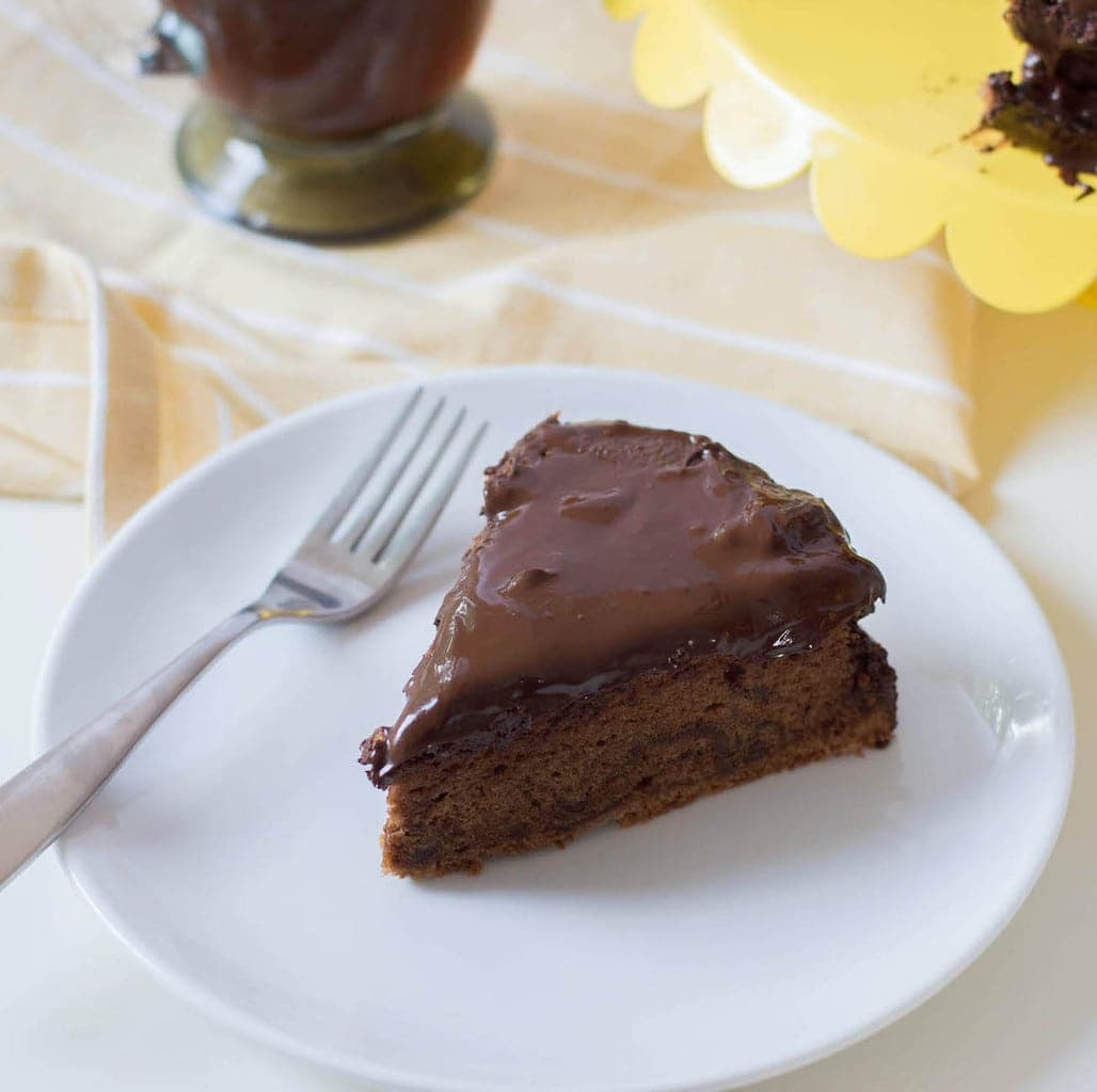 chocolate torte in white plate with yellow tray and coffee in background
