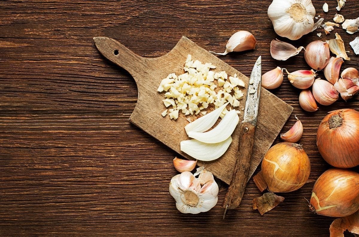 onions and garlic on wood cutting board
