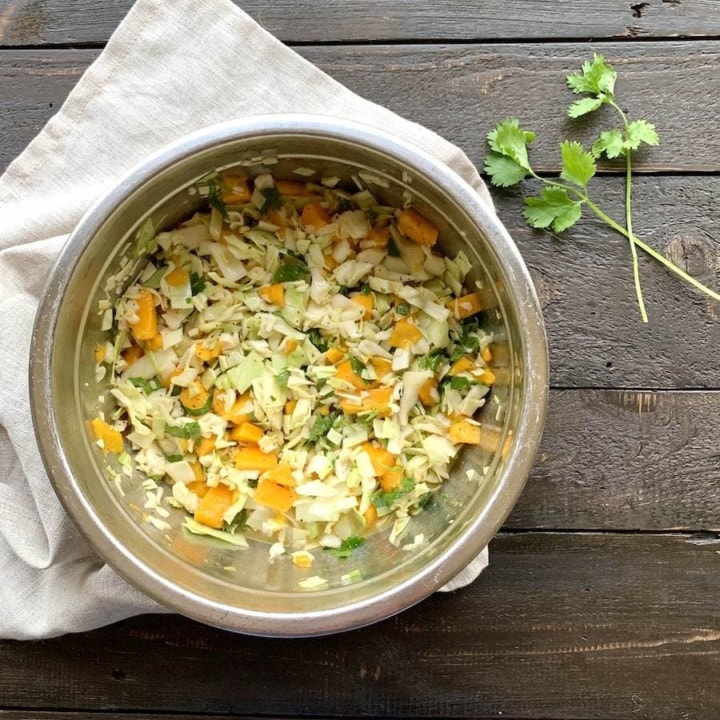 mango, cabbage, cilantro slaw in a silver bowl on a white napkin on a black board