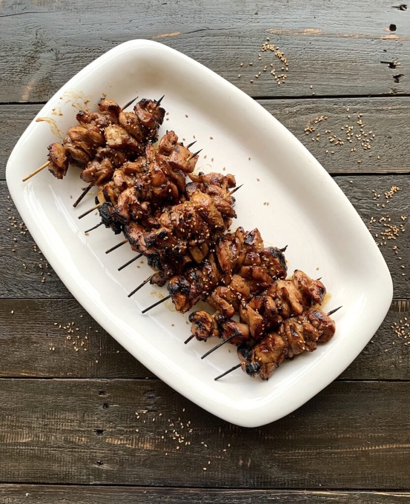 chicken skewers on white plate on black table