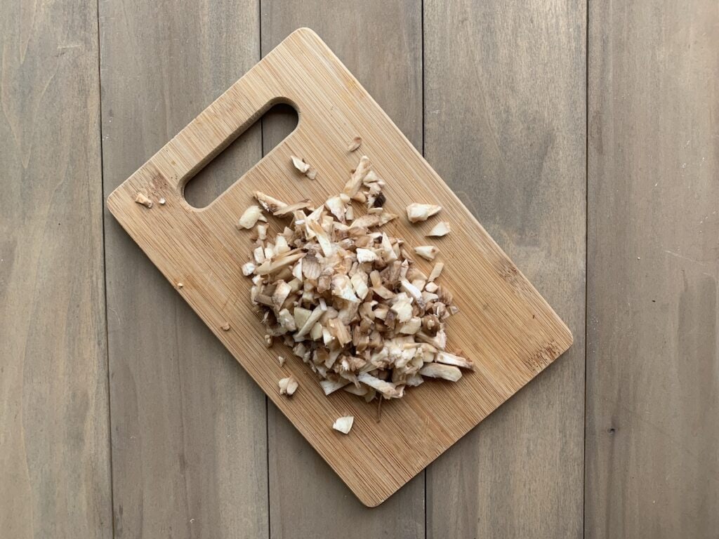Chopped mushrooms stems on cutting board.
