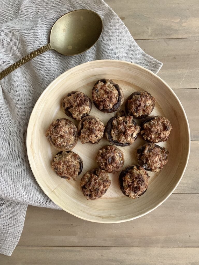 classic stuffed mushrooms in a tan dish with a napkin and serving spoon