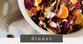 Beet, lettuce, orange sections, feta, and pecans with balsamic dressing in a white bowl.