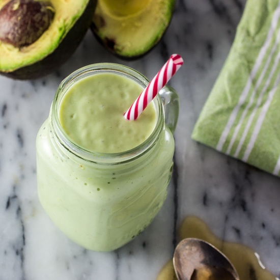 Green milkshake in a mason jar with a red and white straw.
