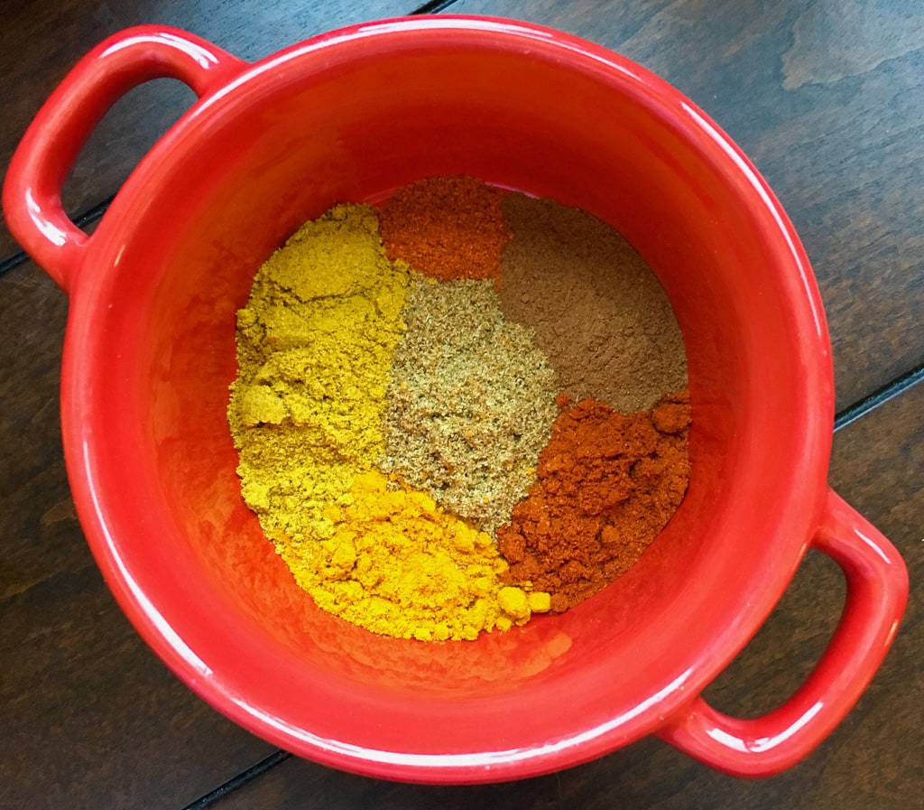 Spice in a red bowl on a black table.