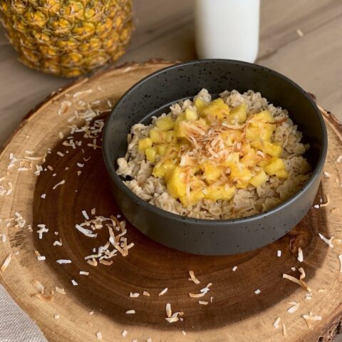 Tropical coconut oatmeal porridge on wood slab.