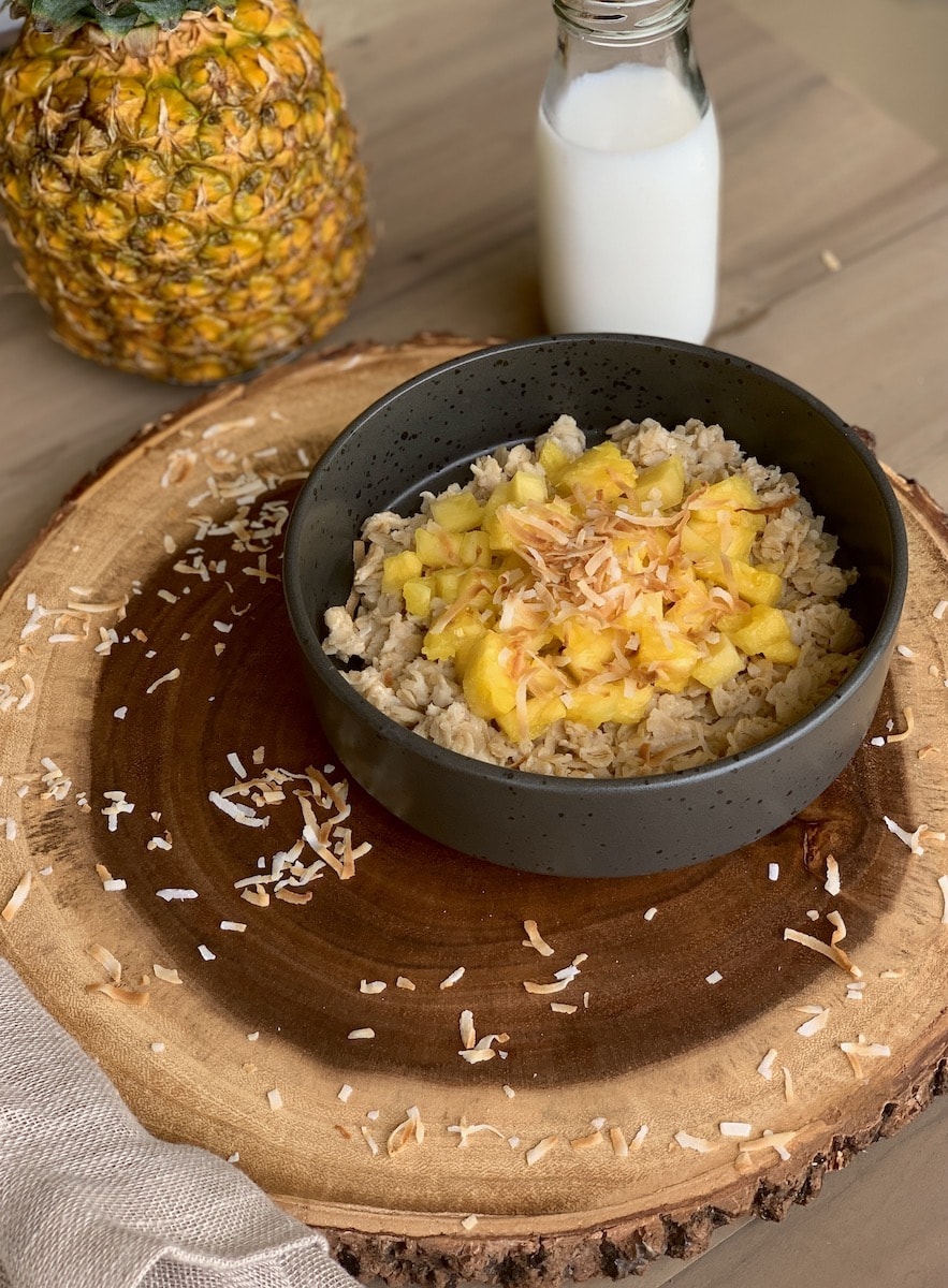 Tropical coconut oatmeal porridge on wood slab.