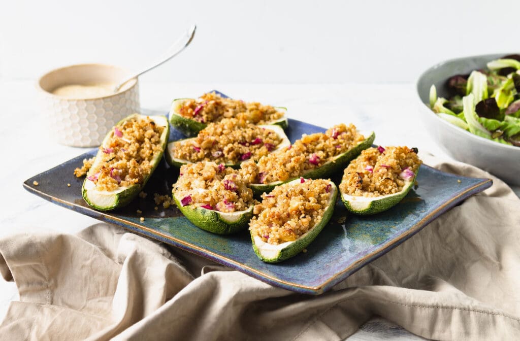 stuffed zucchini on platter with sauce and salad on side