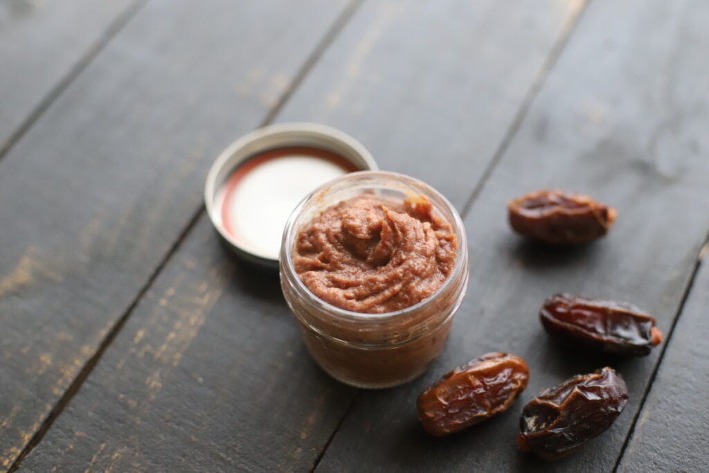 Date paste in a small mason jar with dried dates on side.