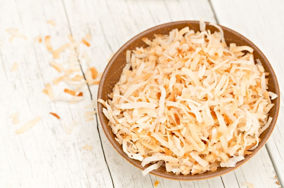 toasted coconut in brown bowl on white table