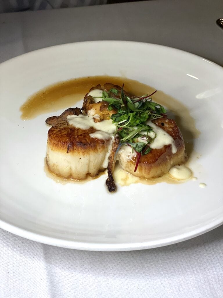 Scallops on a white plate at Chateau Anna Maria restaurant.