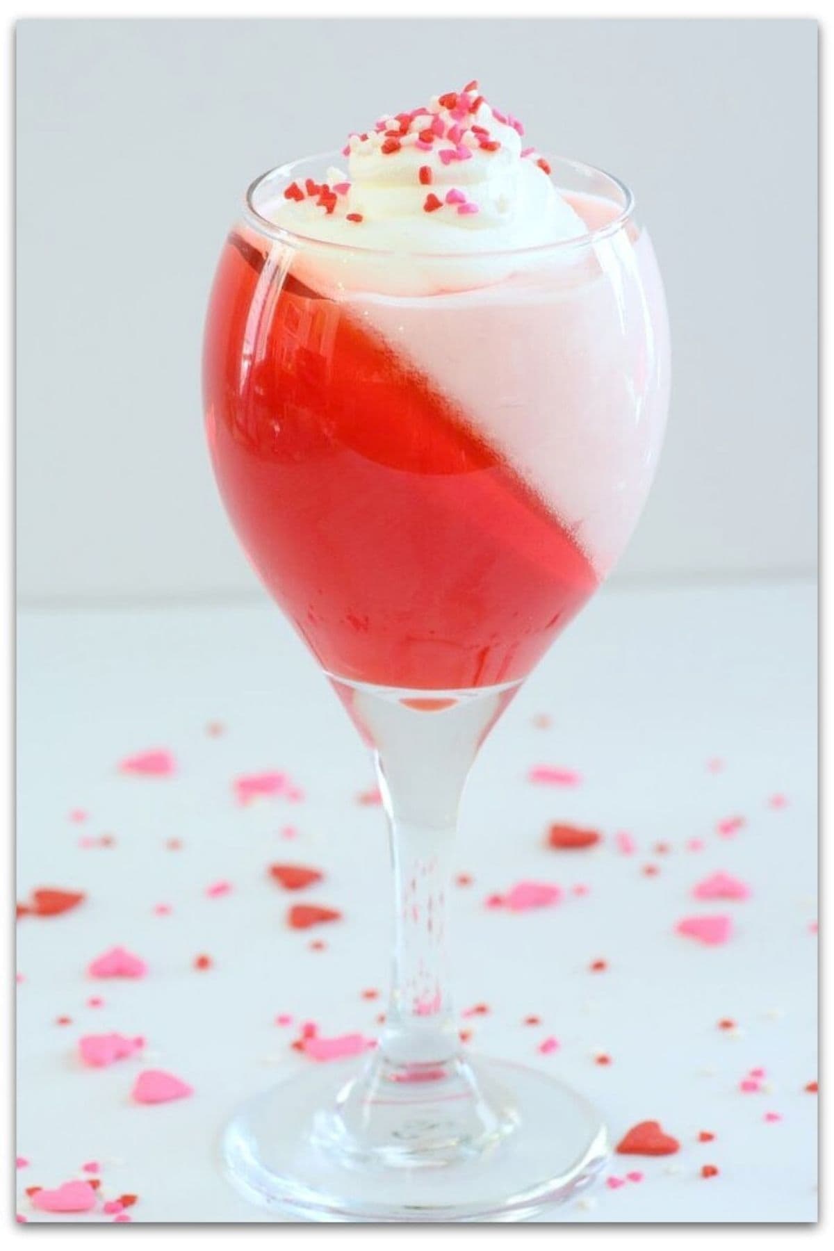 Red jello parfait with whipped cream in a tall glass.