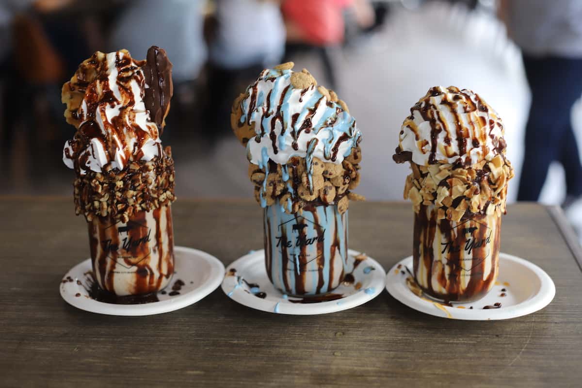 Three milkshakes on a wood table.