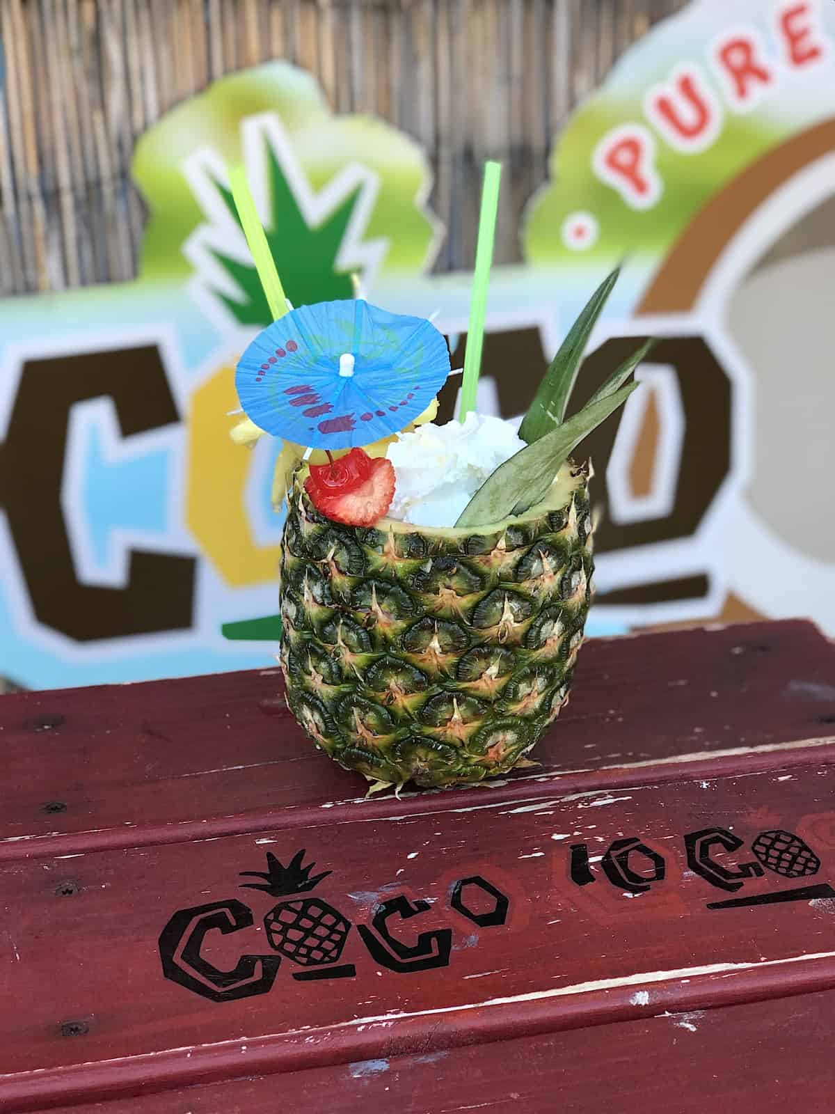 Drink in a pineapple with whipped cream and a cherry and a straw.