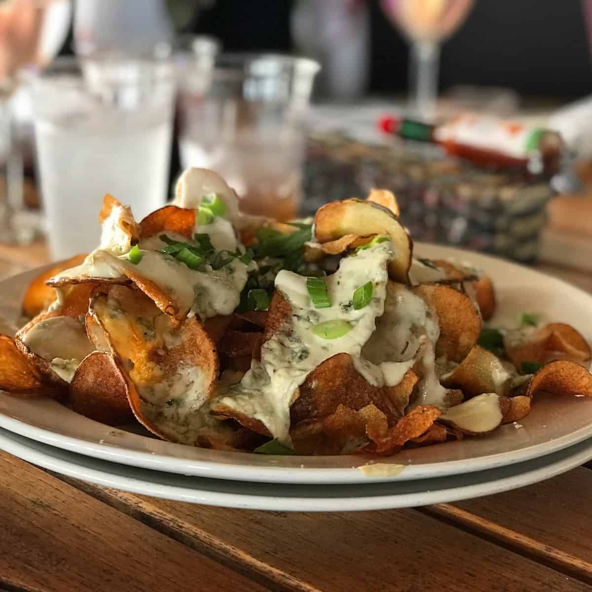 Plate of homemade potato chips with cheese and onions.