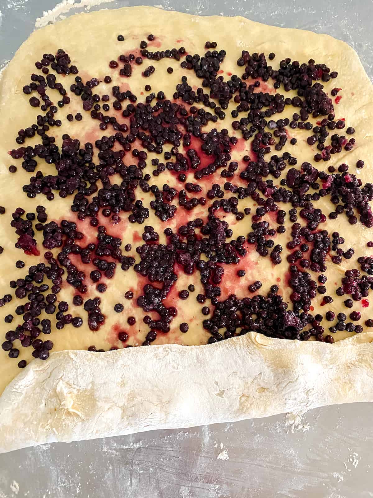 Blueberries spread over dough.