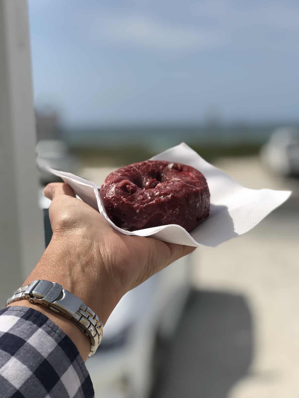 Red velvet doughnut with beach in background.