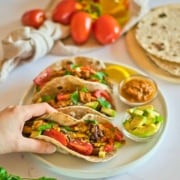 Quinoa tacos on a plate with hand holding one.