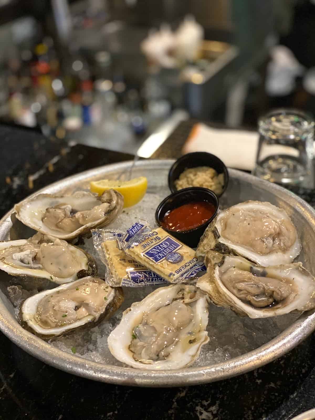 Oysters, cocktail sauce, and crackers on a tray of ice.