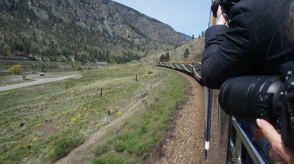 People with cameras taking photos of landscape on train.