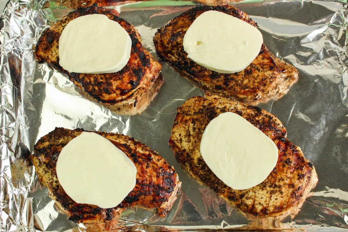 Grilled chicken on foil topped with mozzarella.