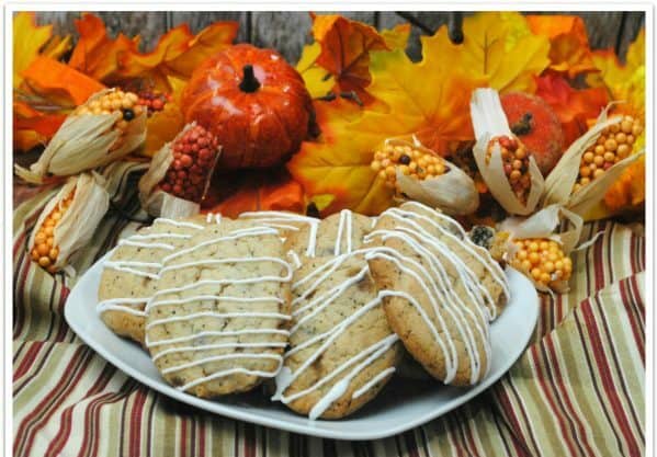 Cookies with icing on white plate with fall decor in background.