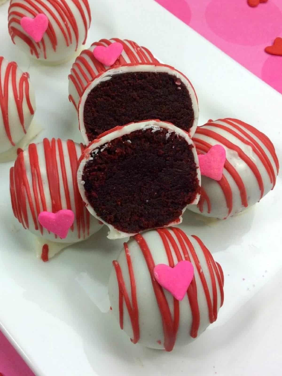 Red velvet cake balls with one cut in half with cake showing.