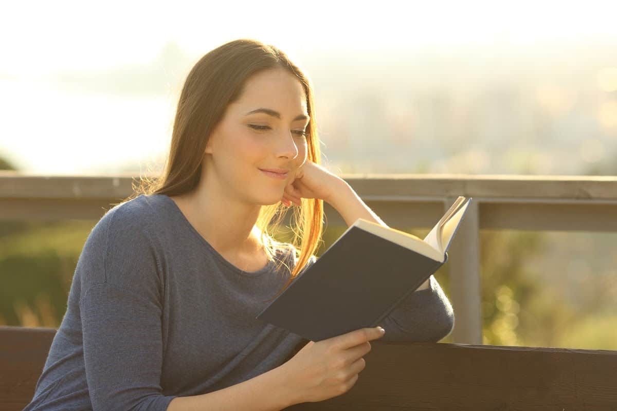 Woman sitting on bench outside reading the Bible.