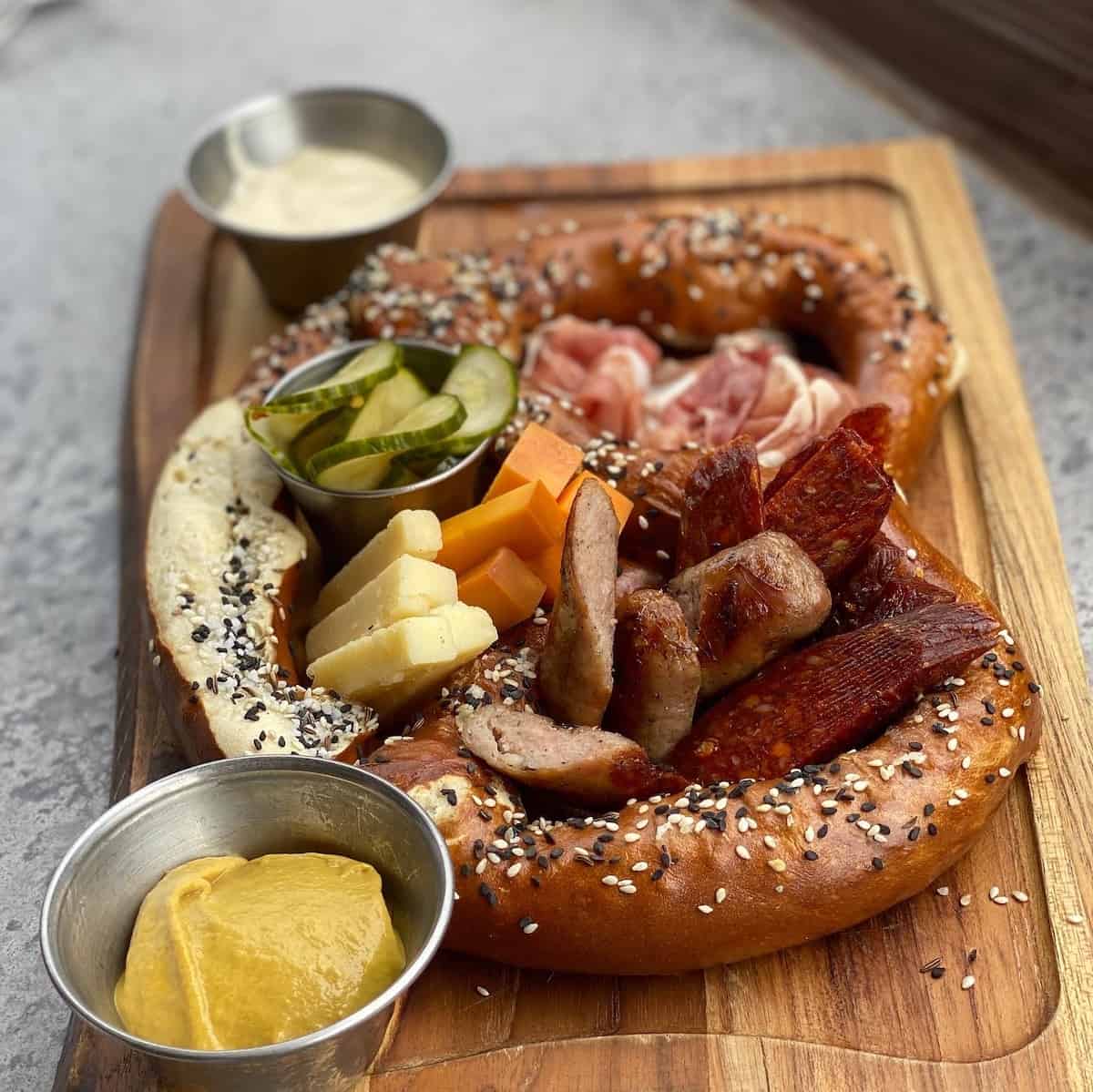 Pretzel with sausage, cheese, prosciutto, and pickles.