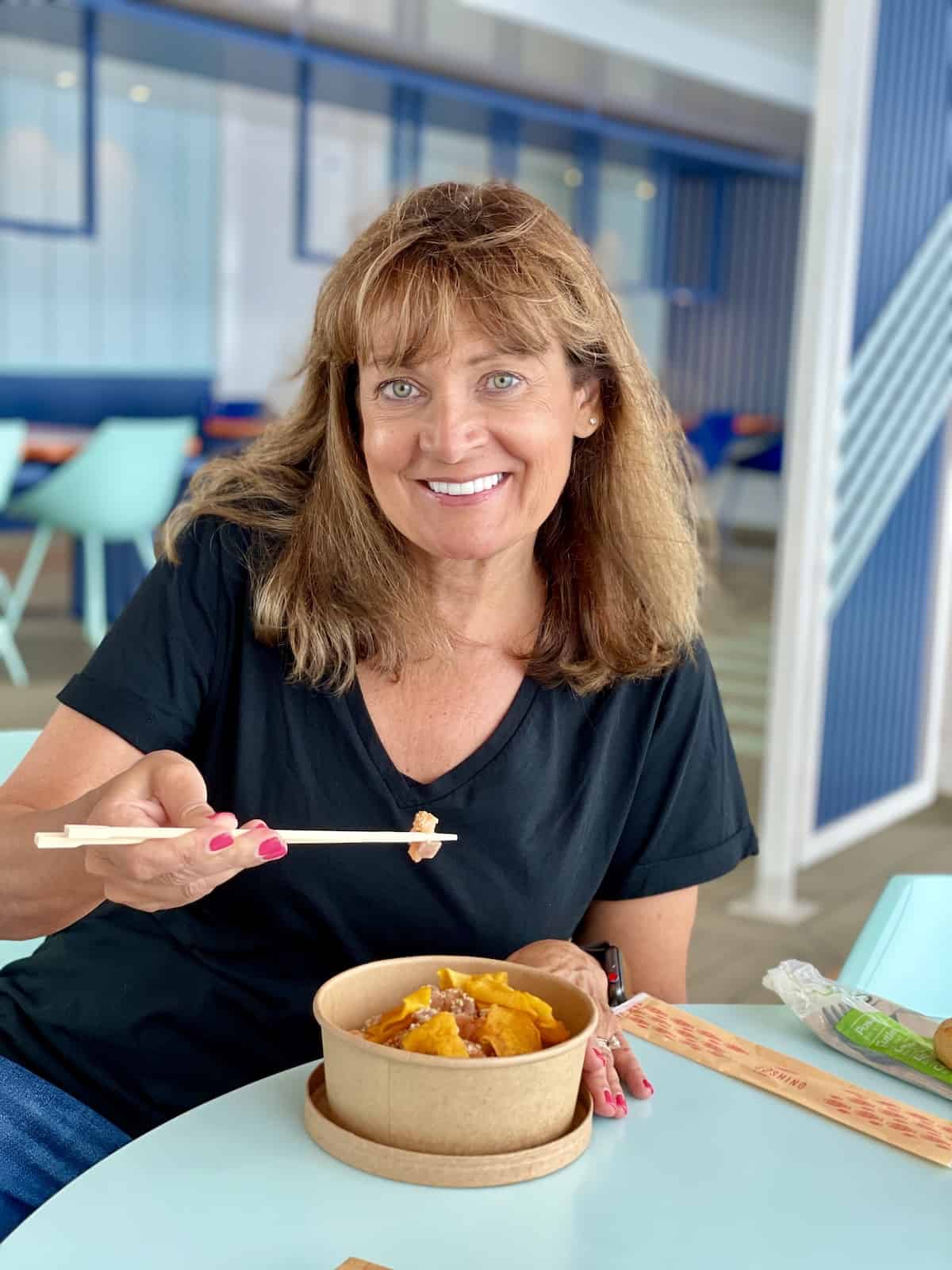 Woman eating Costa Smeralda Poke Bowl.