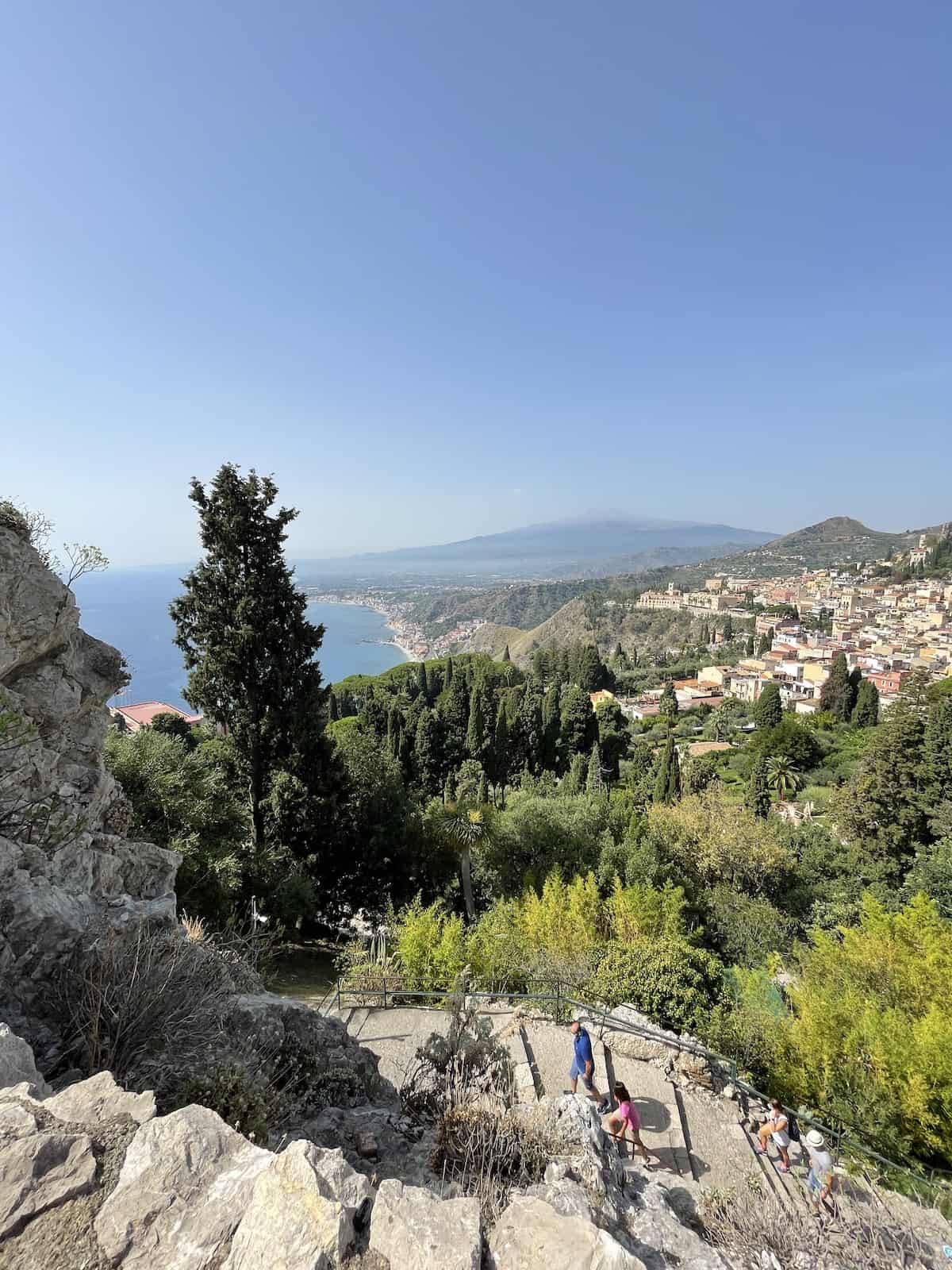 People walking up stairs and view from Taormina Italy