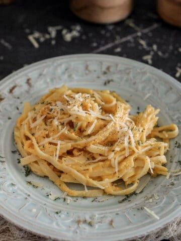 Pasta in a creamy sauce on a light grey plate.