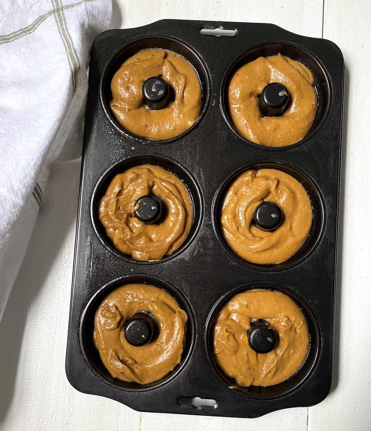 Donuts in a donut pan before baking.