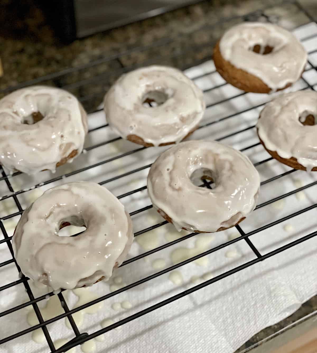 Donuts with icing on a wire rack.